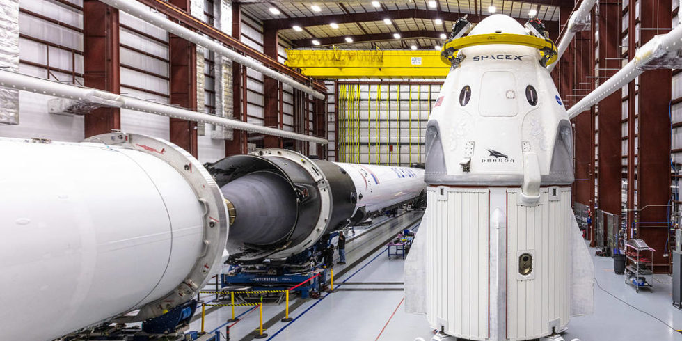 SpaceX-Raumkapsel Crew Dragon und die Falcon 9 Rakete stehen nebeneinander im Hangar