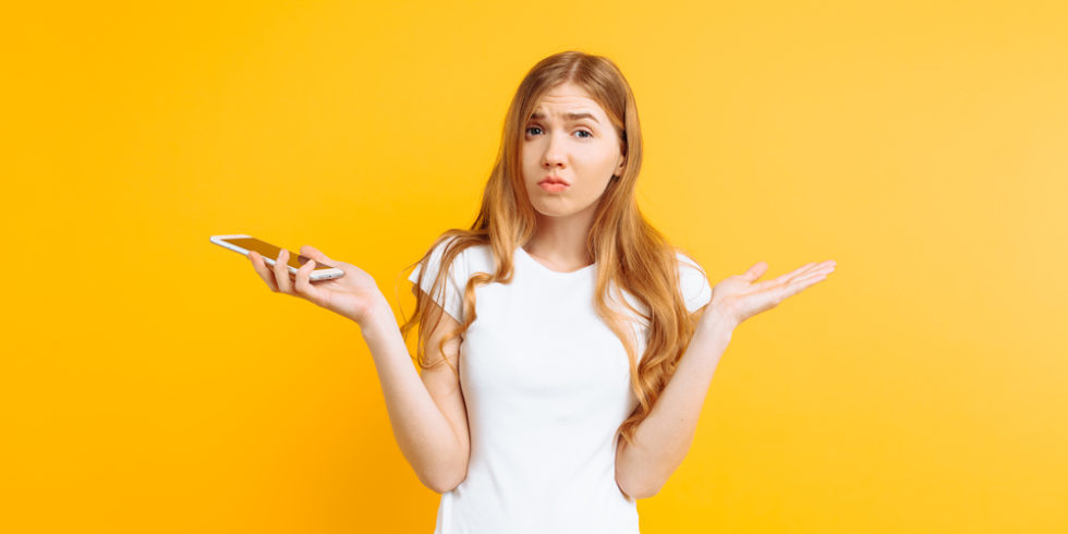 Absage auf eine Bewerbung Schmuckbild: Frau mit Handy in der Hand schaut unsicher