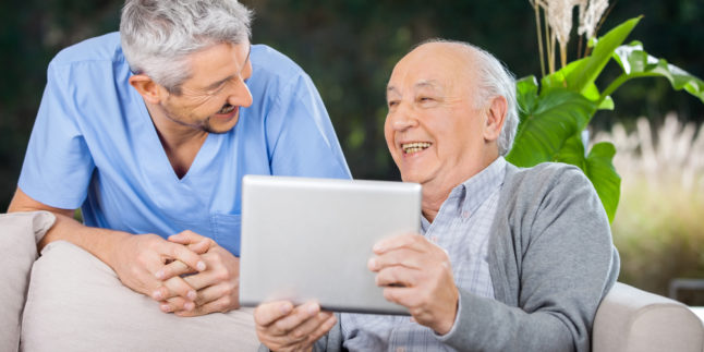 Zwei Männer schauen sich an, der ältere hält ein Tablet