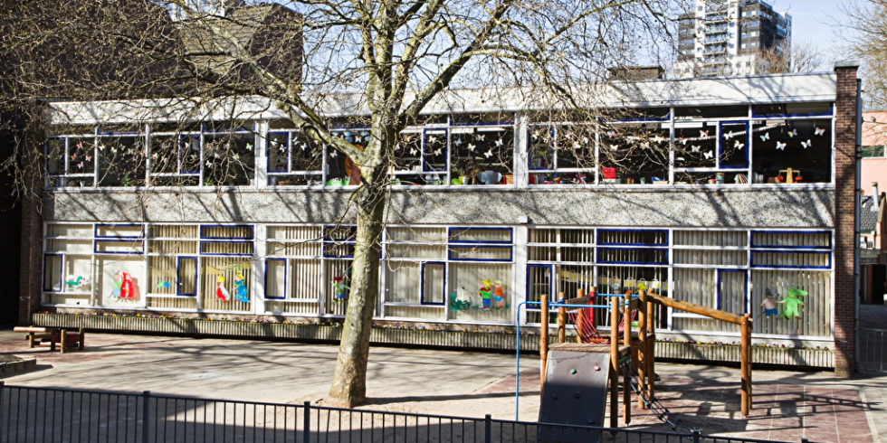 Gebäude mit vielen Bastelarbeiten in den Fenstern und Hof davor, vermutlich ein Kindergarten