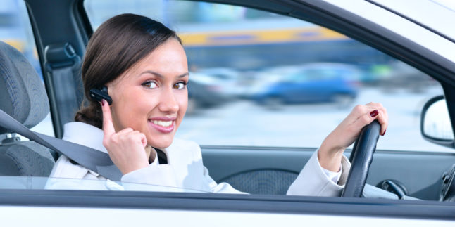 Frau mit Bluetooth Sprechanlage im Auto