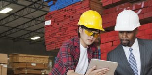 Frau und Mann mit Sicherheitshelm in einem Lager vor Paletten