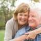 Junggebliebenes Rentnerpaar lachend im Grünen