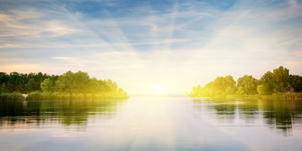 Fluss vor Landschaft mit Sonnenschein