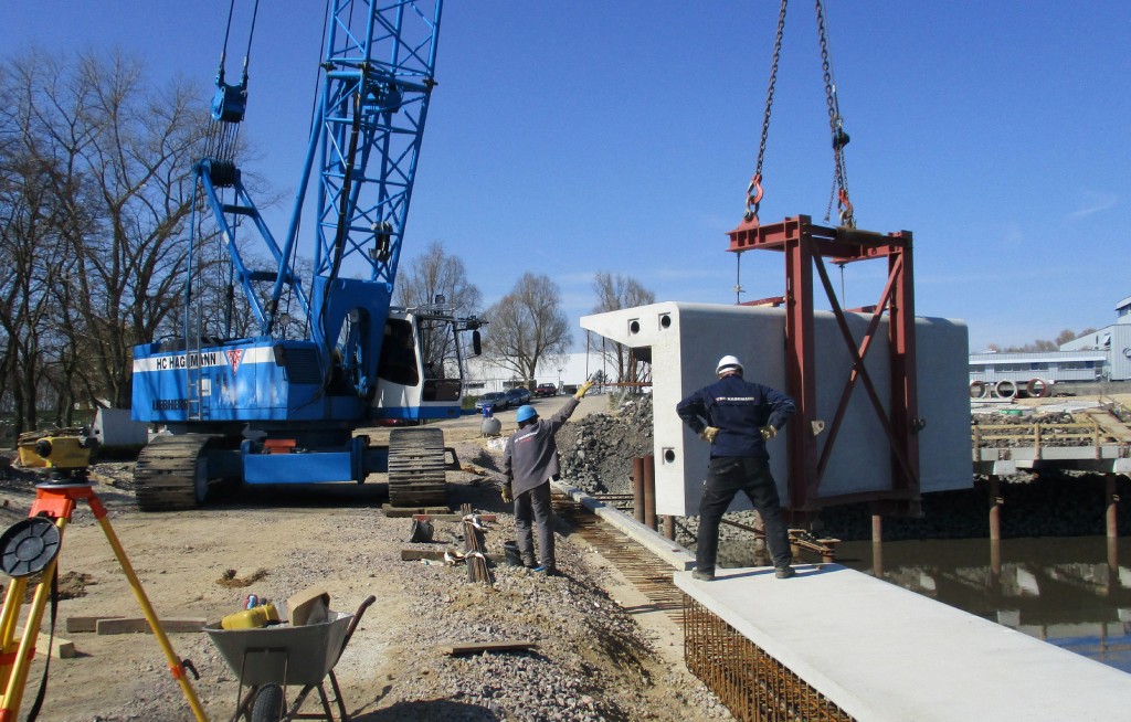 Bild 3. Mit einem 90 Tonnen Seilbagger werden die Winkelabdecksteine am Westufer eingebaut. Abb.: HC Hagemann