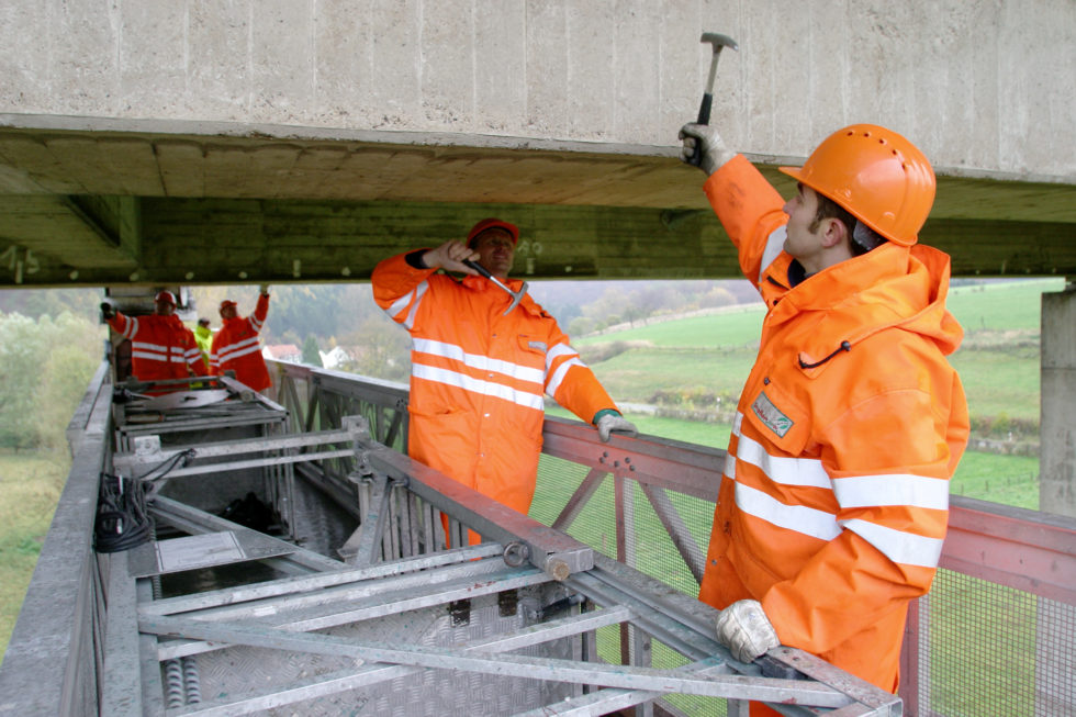 Brückenprüfer mit Hammer unter Brücke