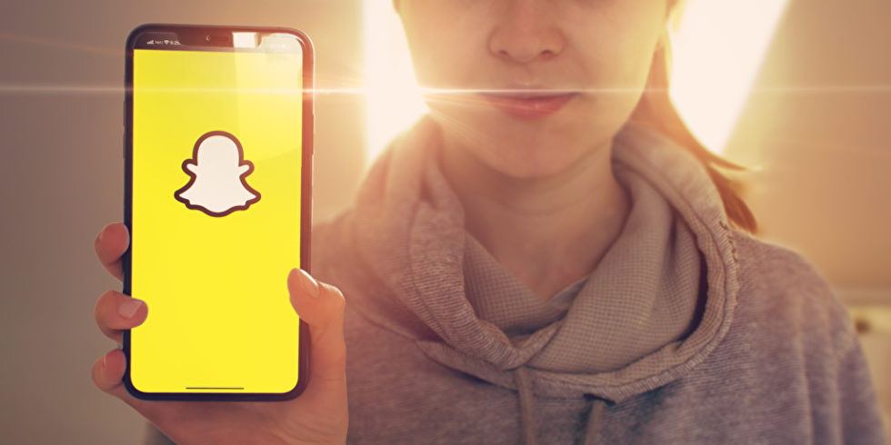 Snapchat auf dem Handy Frau hält es im Hintergrund