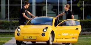 Zwei junge Männer stehen am gelben E-Auto Luca