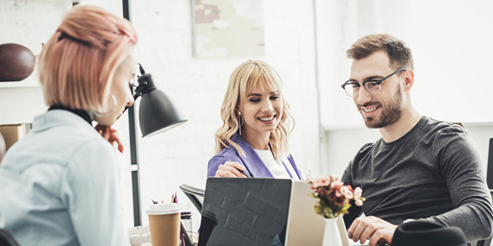 Drei Menschen sitzen im Büro