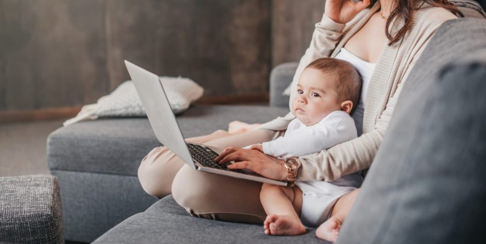 Frau mit Baby auf dem Schoß davor Laptop