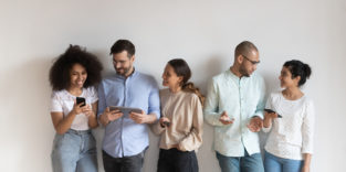 Menschen unterschiedlicher Herkunft stehen zusammen und haben Endgeräte in der Hand