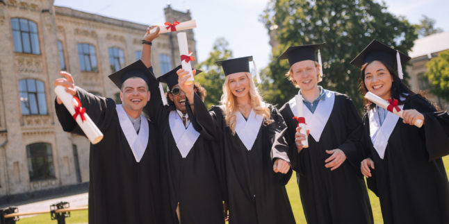 Studierende Abschluss stehen draußen mit Urkunde