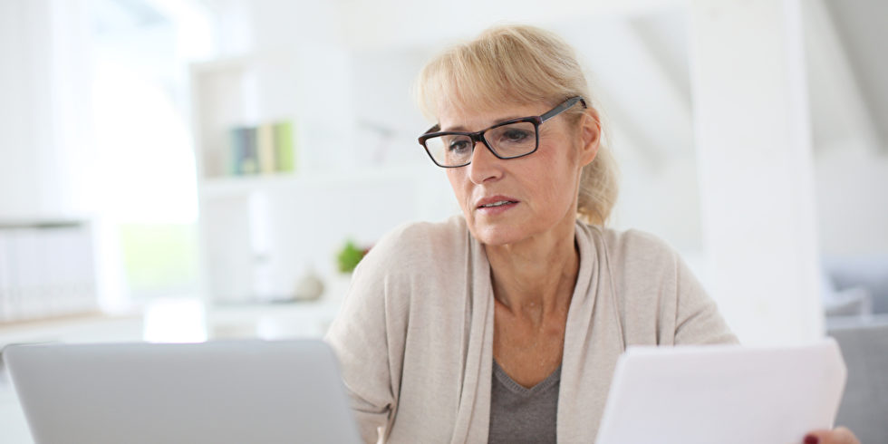 Frau am Laptop mit Papier