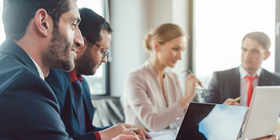 Business-Leute im Gespräch am Konferenztisch mit Laptop