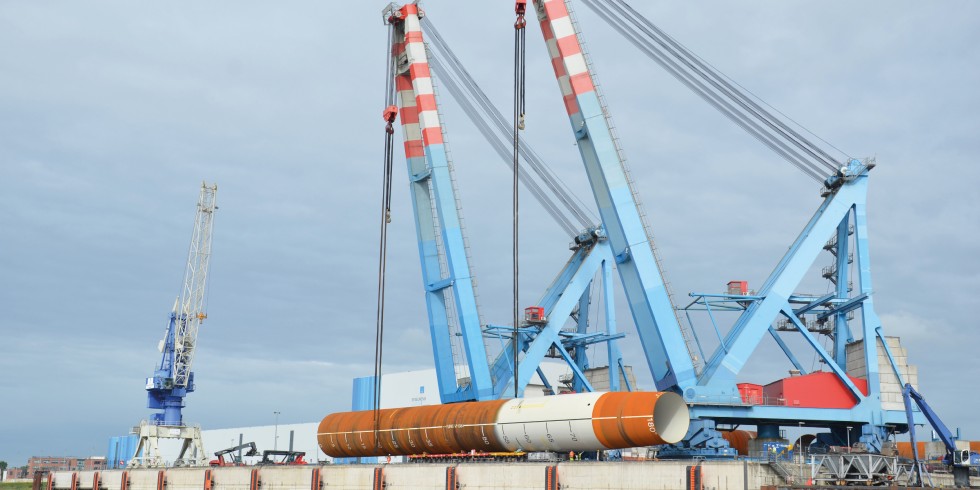 Ein Monopile wird im Steelwinds Hafen von Nordenham verladen. Er wiegt 1 450 t, ist 83 m lang und hat einen Durchmesser von 8 m. Die rostbraunen Teile sind unbeschichtete Stahl-Oberflächen, die hellen korrosionsschutzbeschichtete Flächen. Foto: Ralf Hubo