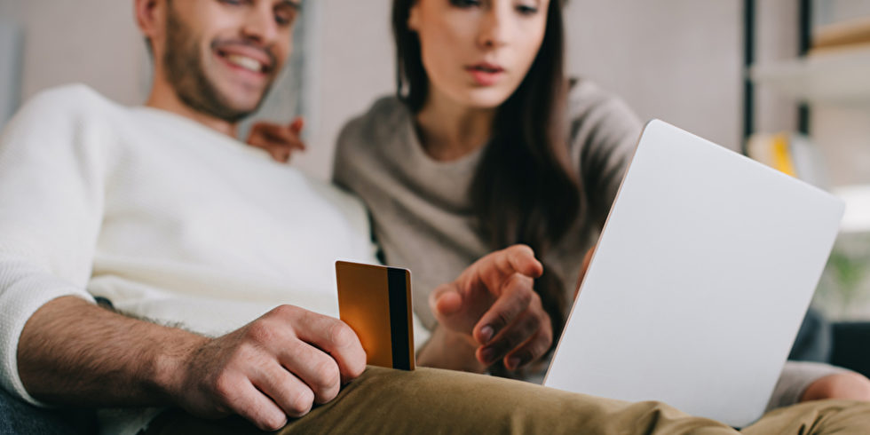 Mann und Frau mit Kreditkarte vor Laptop