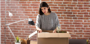 Frau räumt Schreibtisch leer, Karton
