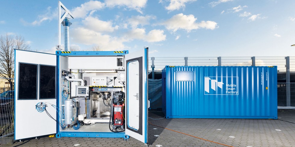 Die "Mobile Smart Factory" besteht aus zwei Containern: Einer enthält die Anlage für die additive Fertigung und die Fräsarbeiten sowie den Rundtisch zur Positionierung der Werkstücke (links im Bild). Der andere Container dient zur Arbeitsvorbereitung und Steuerung der Anlage sowie als Materiallager. Foto: Ulrich Perrey 