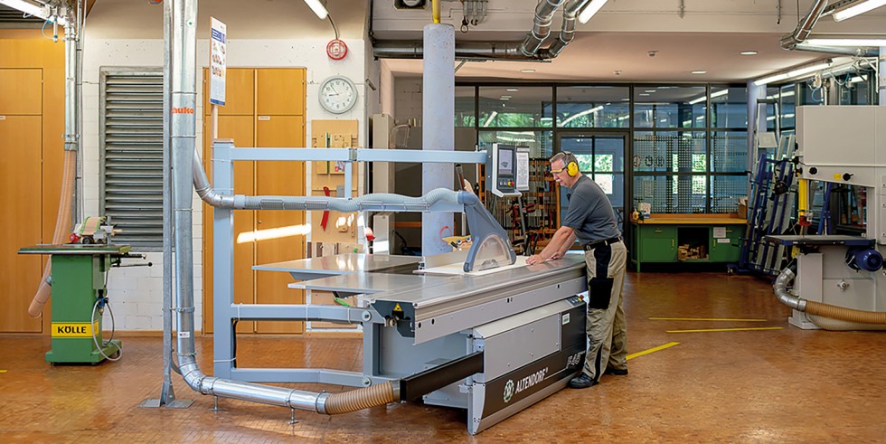 Tischler arbeitet an einer Formatkreissäge mit abgesaugter Schutzhaube und Absaugung unterhalb des Tisches. Foto: ©Medienglanz – Andreas Pöcking/photograph-erfurt.de 