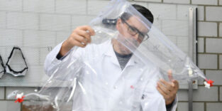 Forschender hält Prototyp einer Matratze für Neugeborene mit Sensoren in der Hand.