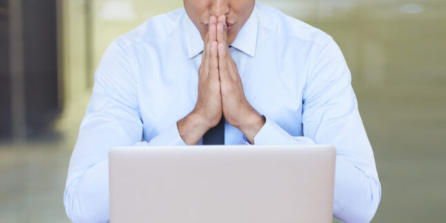 Ein Mann sitzt am Laptop und wartet auf eine Rückmeldung.