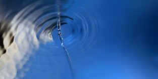 Ein Wasserstrahl verursacht Ringe auf einer Wasseroberfläche