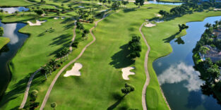 Blick von oben auf einen Golfplatz. Das satte Grün des Rasens wird durchbrochen von kleinen Sandlöchern und umrahmt von kleinen Seen.