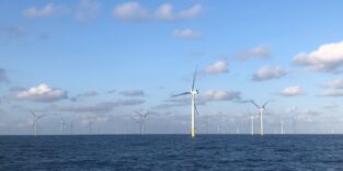 Blick auf Offshore-Windenergieanlagen vor blauem Himmel und sich leicht bewegender See.
