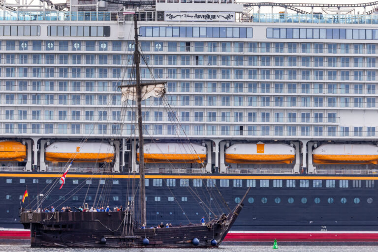 Die «Wisemara», ein Nachbau einer vor der Insel Poel gefundenen alten Kogge, fährt am neuen Kreuzfahrtschiff „Disney Adventure“ am Ausrüstungskai der Wismarer Werft vorbei