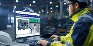 Inside the Heavy Industry Factory Industrial Engineer Works on the Personal Computer with Green Mock-up Screen.