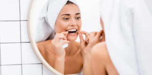 Frau benutzt Zahnseide