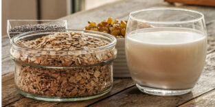 Ein Schälchen Hafer neben einem Glas Haferdrink.