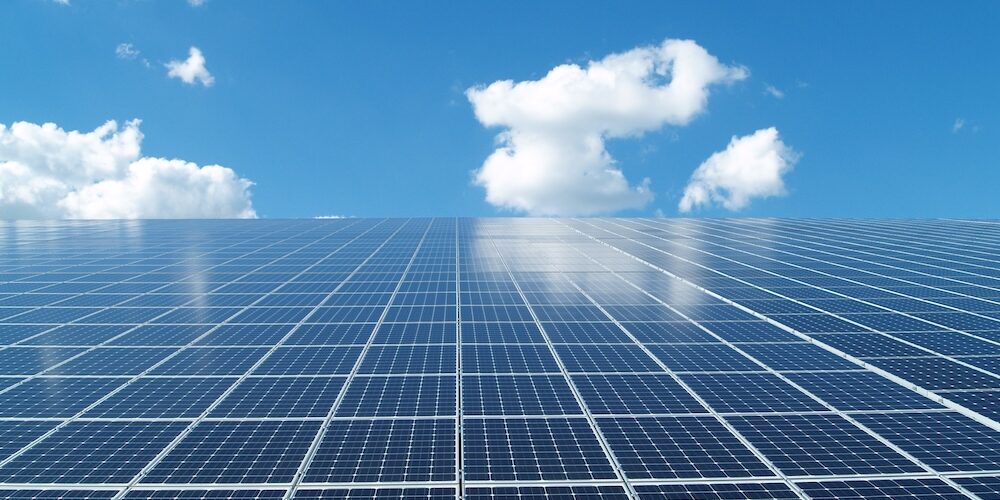 Solarmodule vor blauem Himmel mit leichten Wolken.