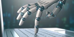 Roboterhand tippt mit einem Finger auf einer Notebook-Tastatur.