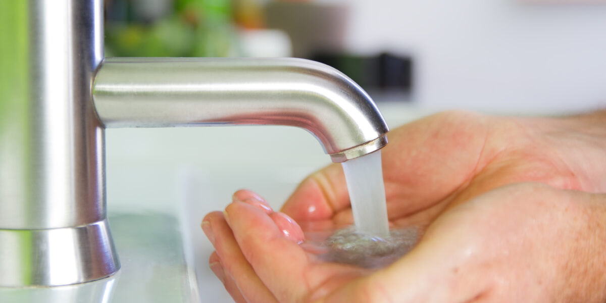 Wasser läuft aus dem Hahn in eine Hand