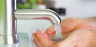 Wasser läuft aus dem Hahn in eine Hand