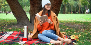 Eine junge Frau sitzt in einem Park und liest.