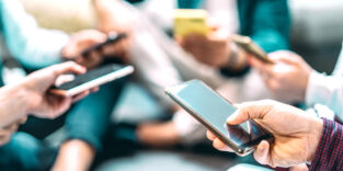 Personen stehen in einer Runde und halten ihre Smartphones in den Händen.