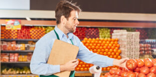 Supermarkt Verkäufer mit Checkliste auf Klemmbrett kontrolliert Gemüse in der Gemüseabteilung