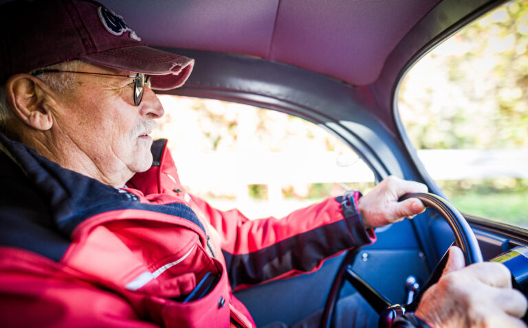 Traugott Grundmann fährt mit seinem VW Käfer eine Landstraße entlang