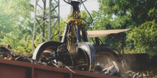 Photo of special claw gripper lfrabbing and lifting metal waste on scrapyard