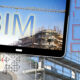 Building Information Modeling, BIM, a new way of architecture designing - concept image with metal scaffolding, tower crane, construction machinery in a construction site and 3D render of a digital table