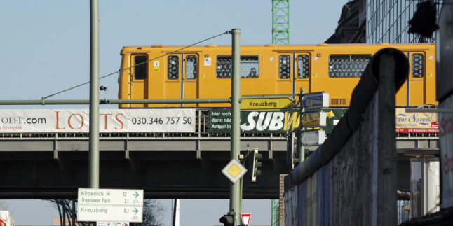 Eine gelbe Berliner Stadtbahn auf einer Brücke.