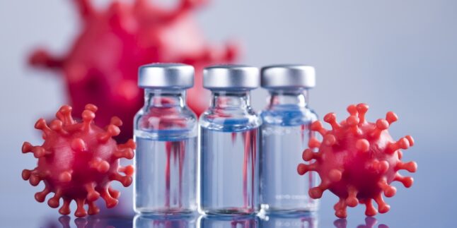 Kleine Gläschen mit Impfdosen und Darstellungen von Viren daneben.