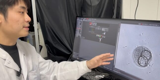 Forscher zeigt mit der linken Hand auf einen Monitor, auf dem eine Knochenzelle zu sehen ist.