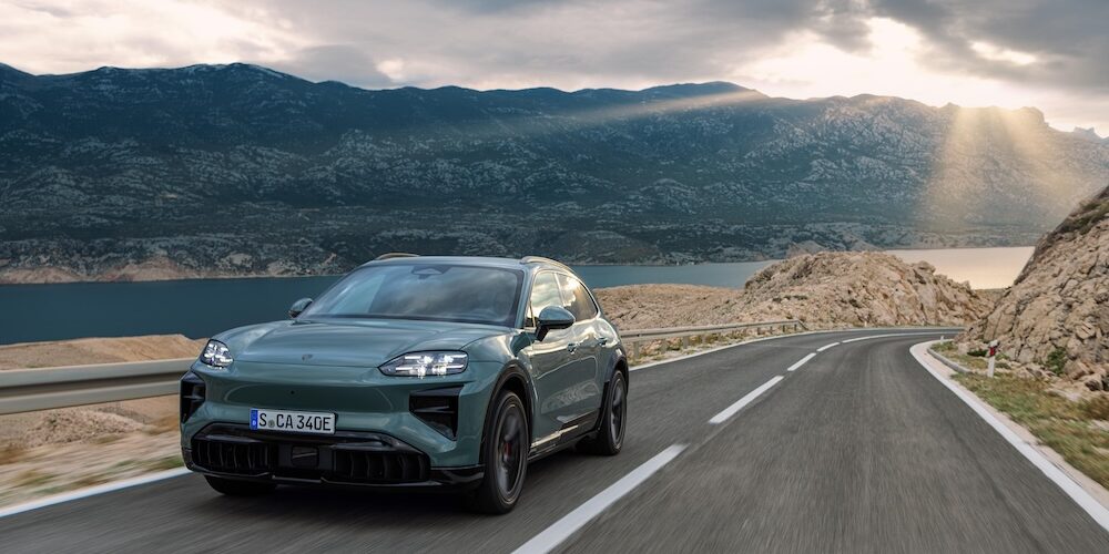 Der neue Porsche Cayenne Electric auf einer Straße in Fahrt und von vorne betrachtet.