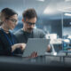 Portrait of Two Creative Young Female and Male Engineers Using Laptop Computer to Analyze and Discuss How to Proceed with the Artificial Intelligence Software. Standing in High Tech Research Office