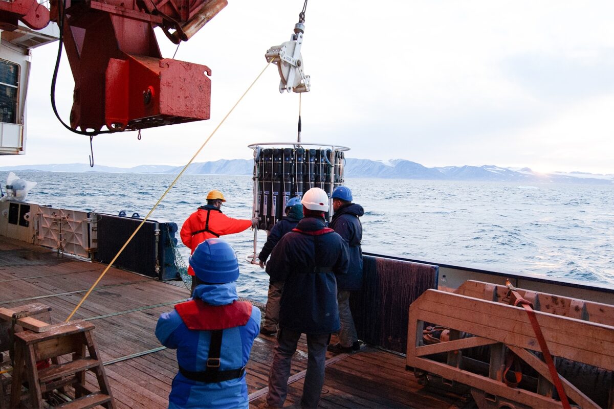 Forschende bei Messungen zum Bleigehalt im Ozean, die Messgeräte von einem Forschungsschiff ins Wasser lassen.
