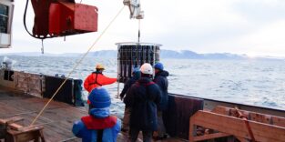 Forschende bei Messungen zum Bleigehalt im Ozean, die Messgeräte von einem Forschungsschiff ins Wasser lassen.