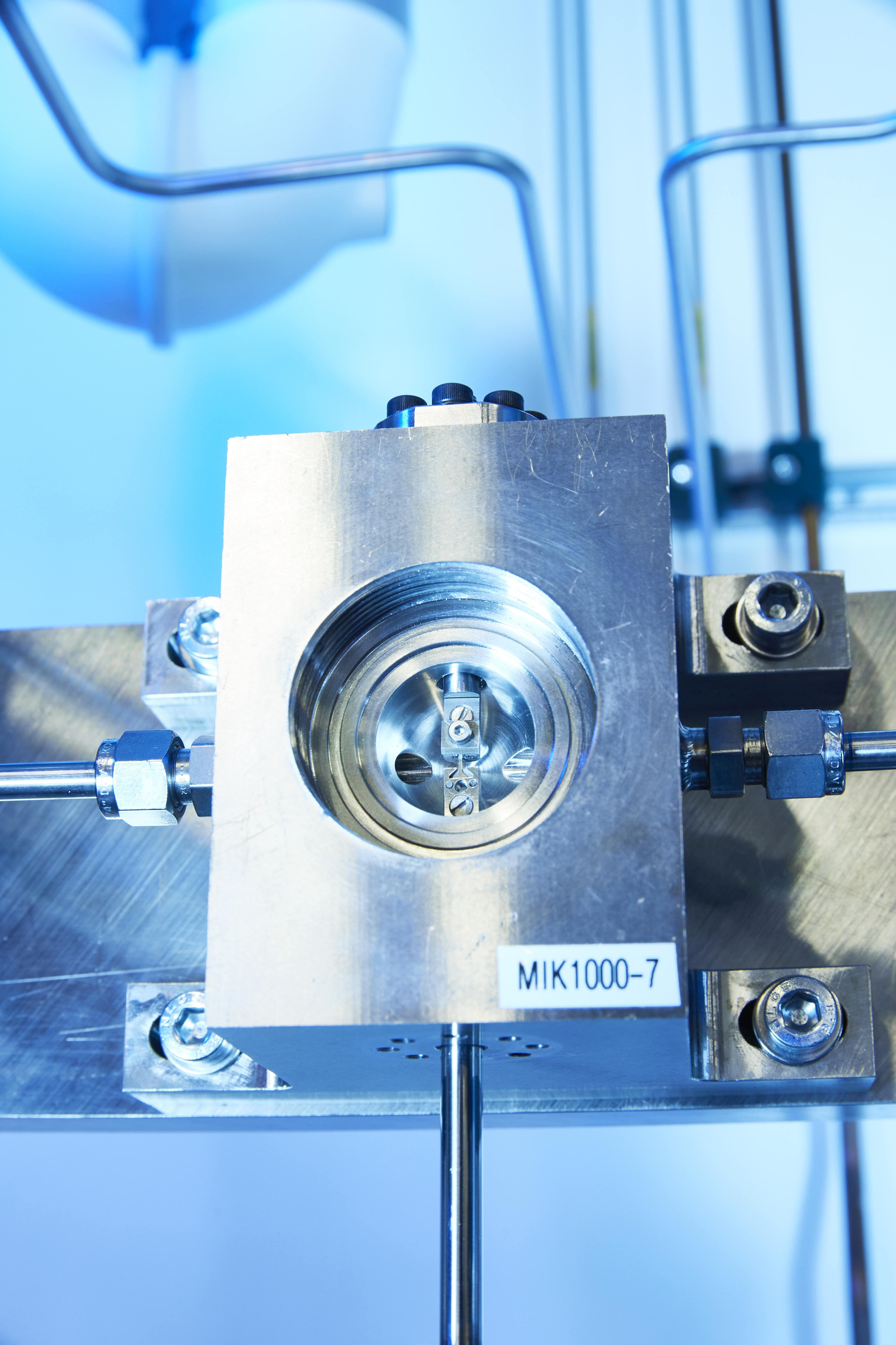 Eine Mikrozugprobe (6 mm Länge, Stegbreite 0,4mm) ist in der Prüfkammer in Probenhaltern montiert. Foto: Fraunhofer IWM, Kai Wudtke